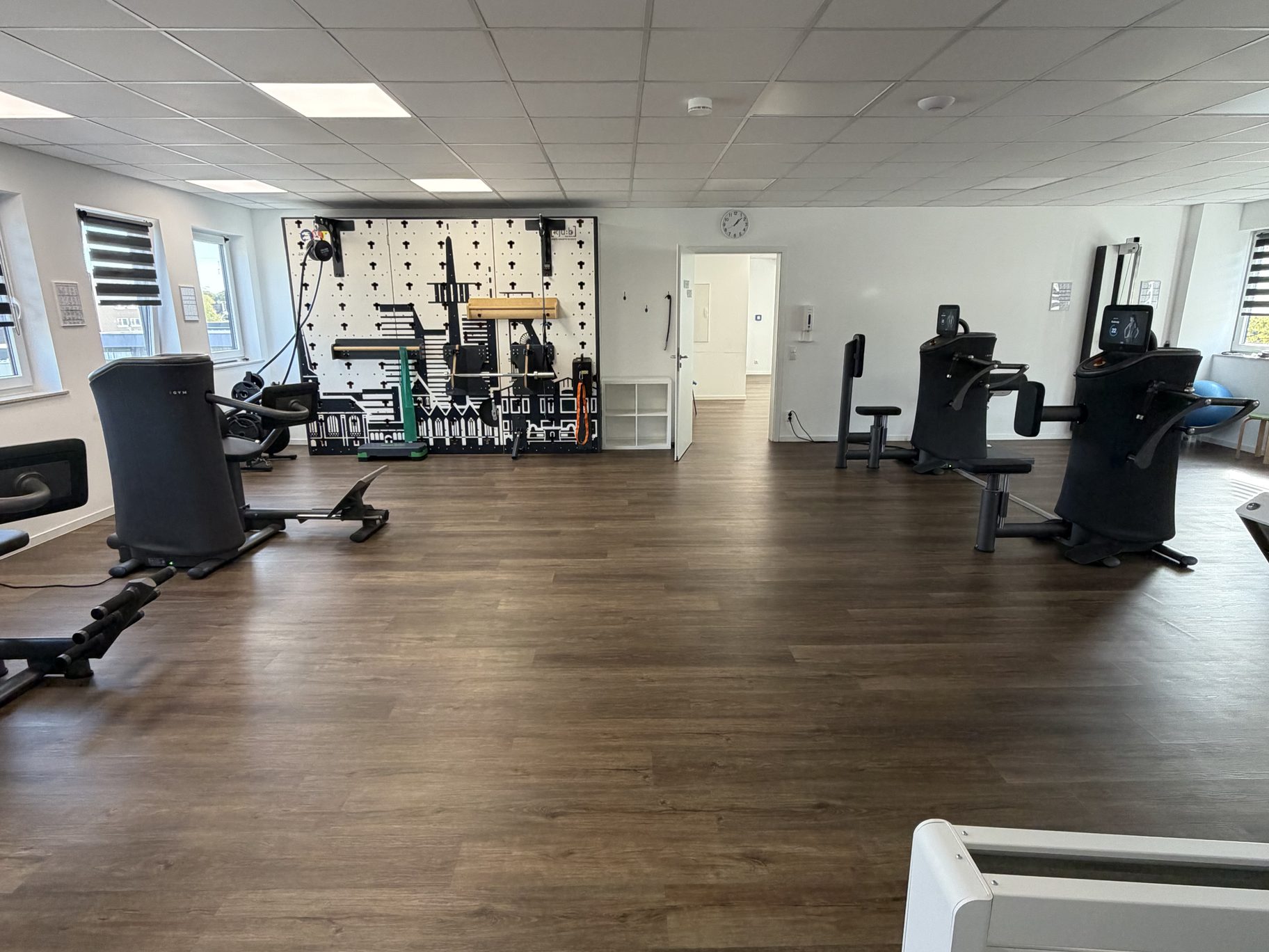 Weite, helle Trainingsfläche mit EGYM-Geräten, Laufband und Trainingswand